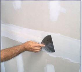 a painter repairing drywall before painting an interior wall 